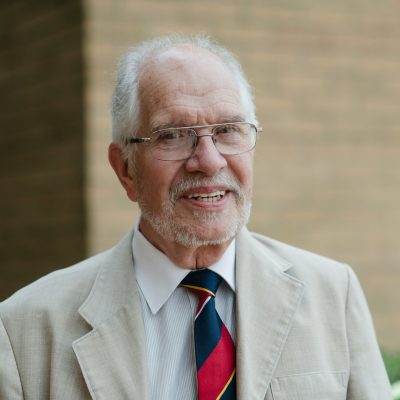 Older man wearing glasses and a suit, smiling in a formal portrait.
