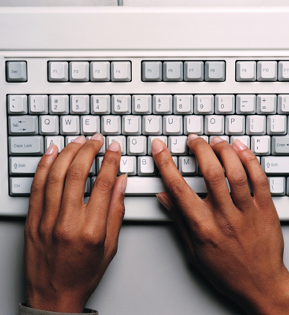 Two hands typing on a white computer keyboard. The fingers rest on the home row, suggesting active typing.
