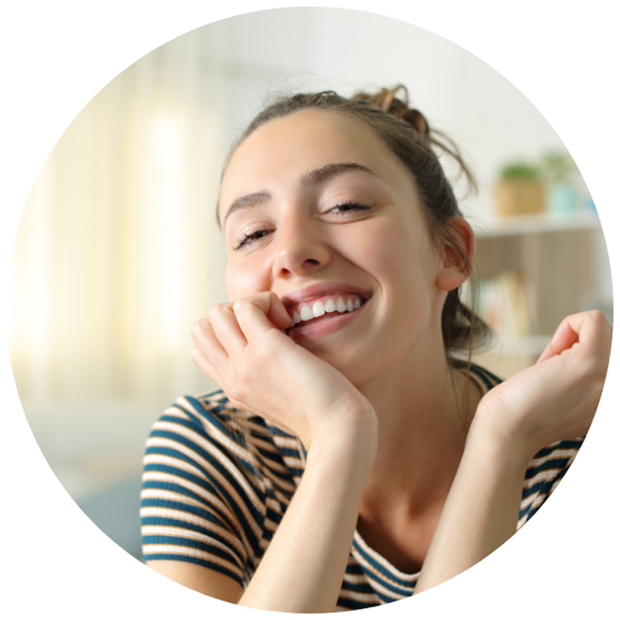Smiling woman in a striped shirt rests her chin on her hands, exuding happiness and warmth.