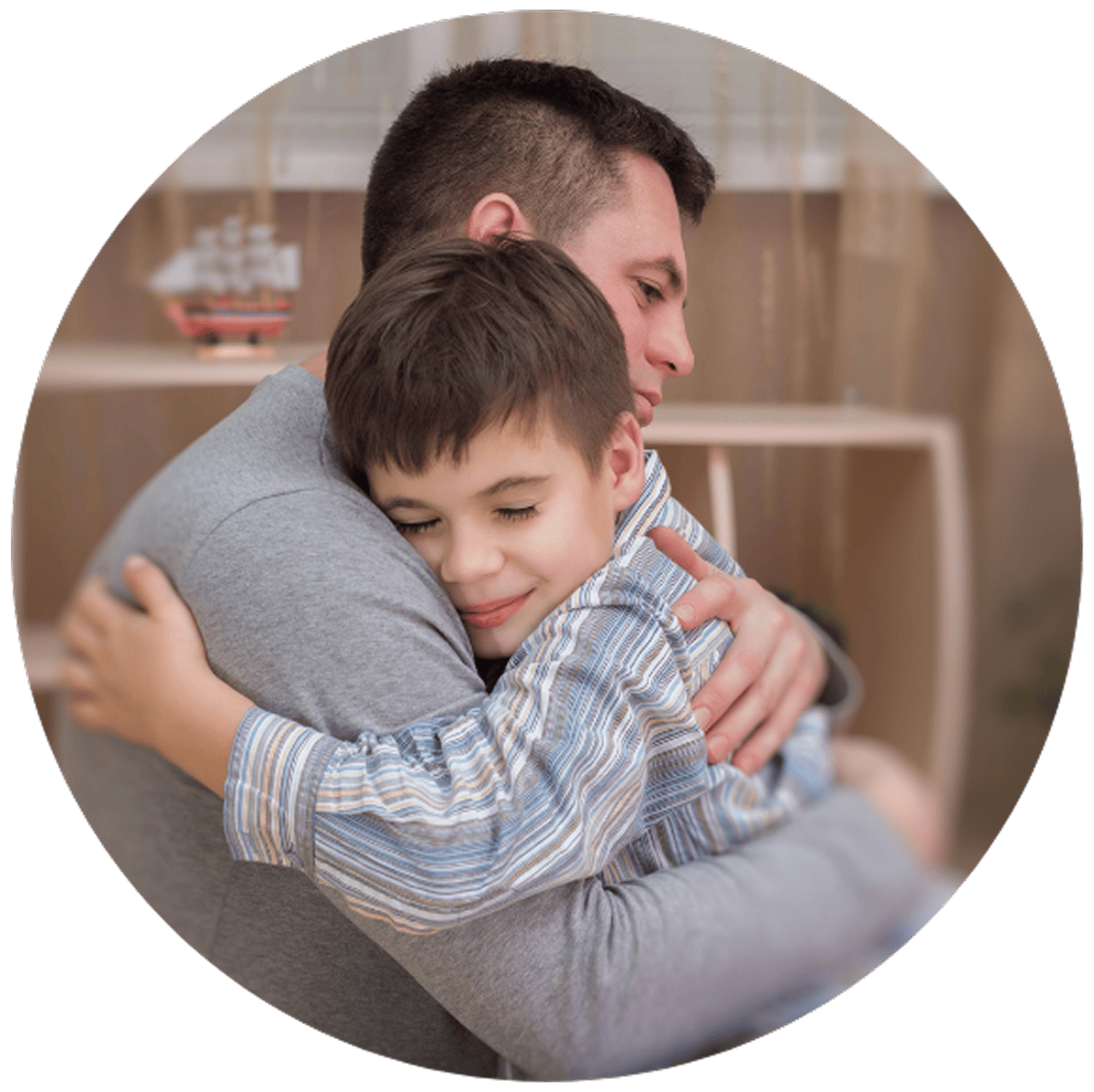 A father and son share a warm embrace, both smiling with eyes closed. The setting is cozy, with soft lighting.