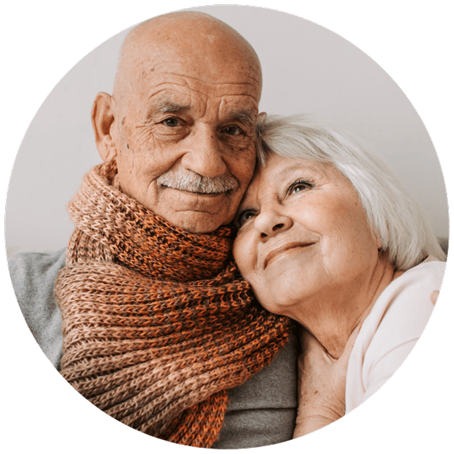 Elderly couple lovingly embracing, man with a knitted scarf, woman resting her head on his shoulder.