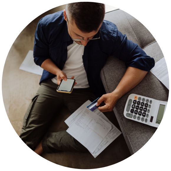 Person reviewing medical bills and paperwork while using a phone and calculator.