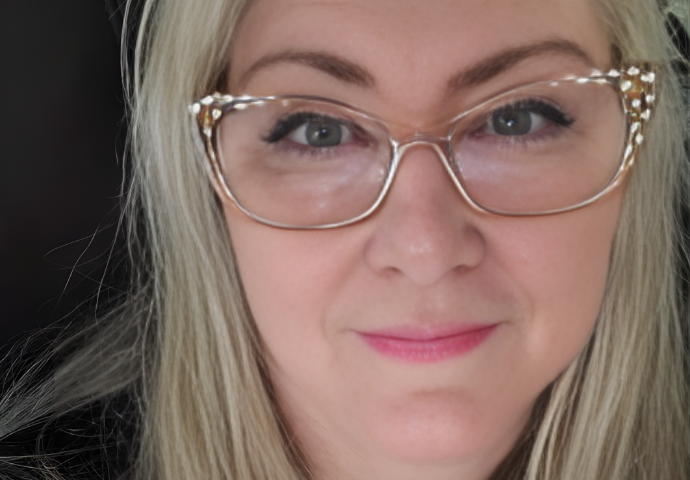 Close-up portrait of an adult woman wearing glasses, looking directly at the camera.