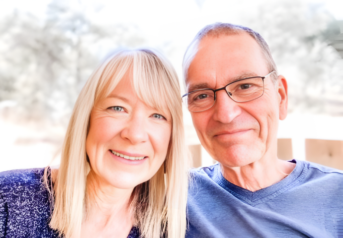 Couple smiling together outdoors in a close, supportive portrait.