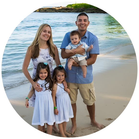 Family with three children standing together on a beach, smiling at the camera.
