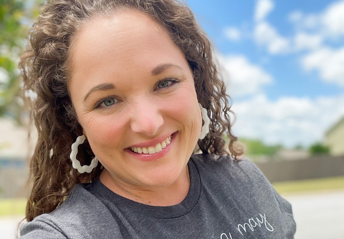 Woman smiling outdoors in a casual portrait on a sunny day.
