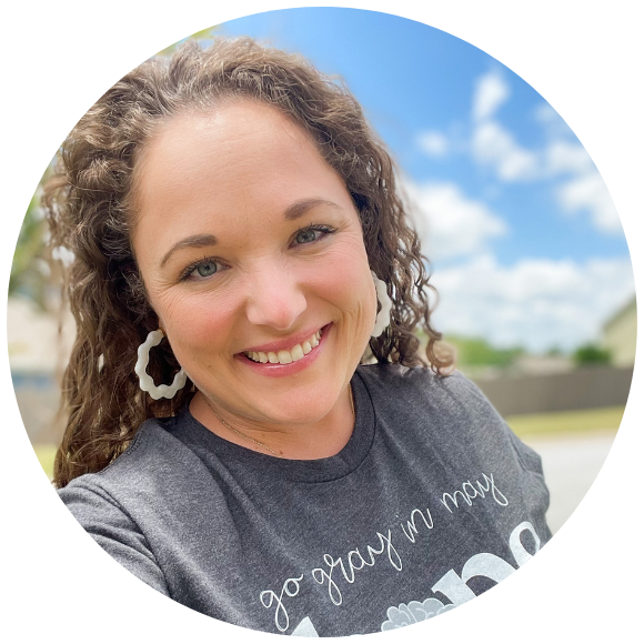 Woman smiling outdoors in a casual portrait on a sunny day.