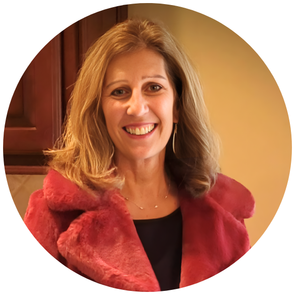 Woman smiling indoors, wearing a red jacket in a warm portrait.