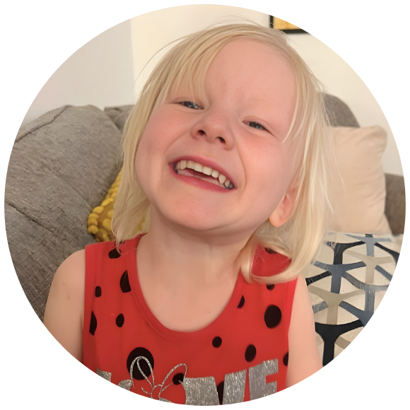 Smiling young child sitting on a couch indoors.