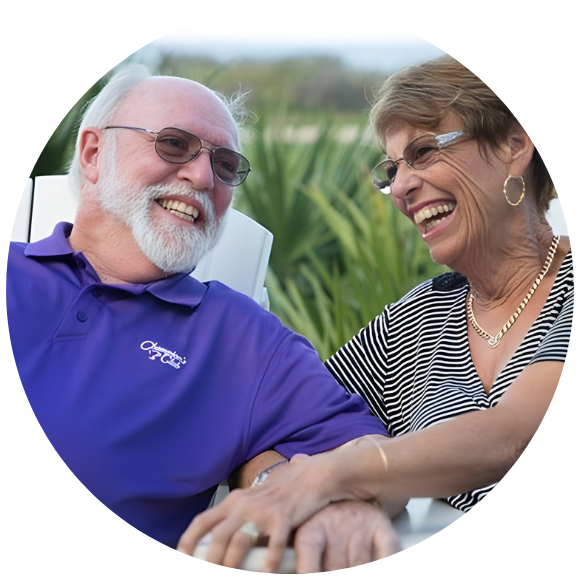 Older couple laughing together outdoors, sharing a relaxed moment.