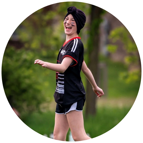 Young person laughing while walking outdoors during a group activity.