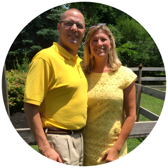 Couple standing together outdoors, smiling in a sunny setting.