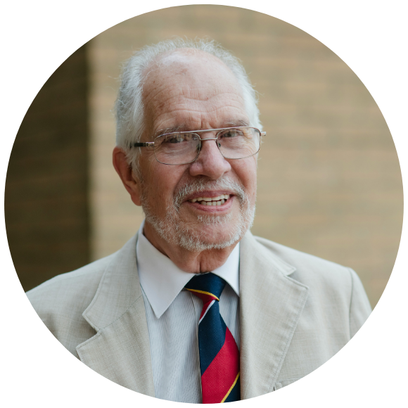 Older man wearing glasses and a suit, smiling in a formal portrait.