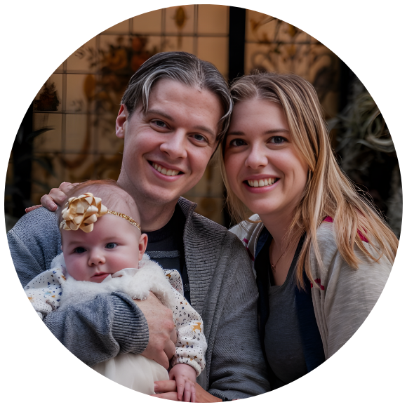 Parents smiling while holding their infant during a family portrait.