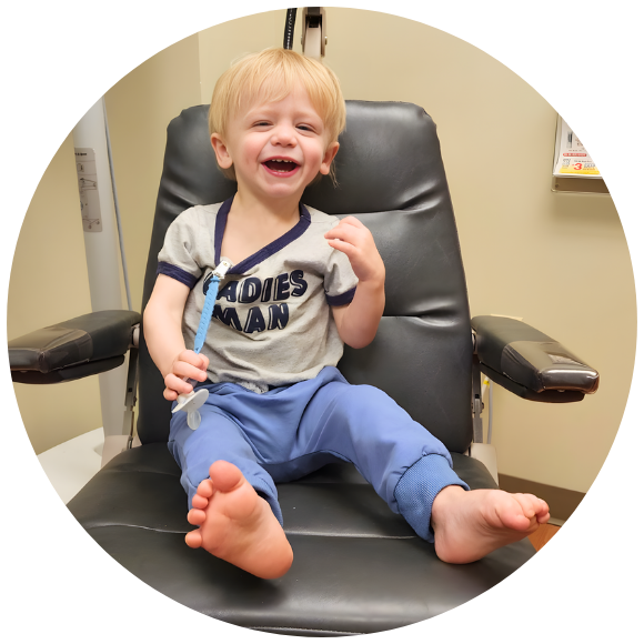 Smiling toddler sitting in a medical chair during a pediatric appointment.