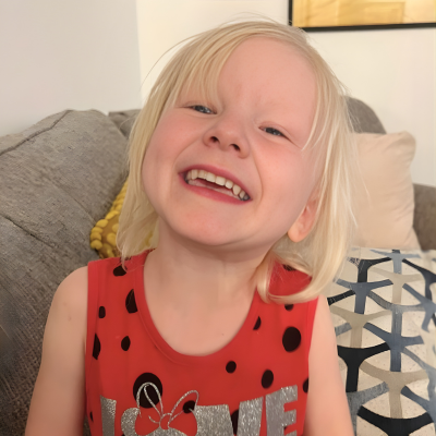 Smiling young child sitting on a couch indoors.