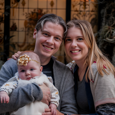 Parents smiling while holding their infant during a family portrait.