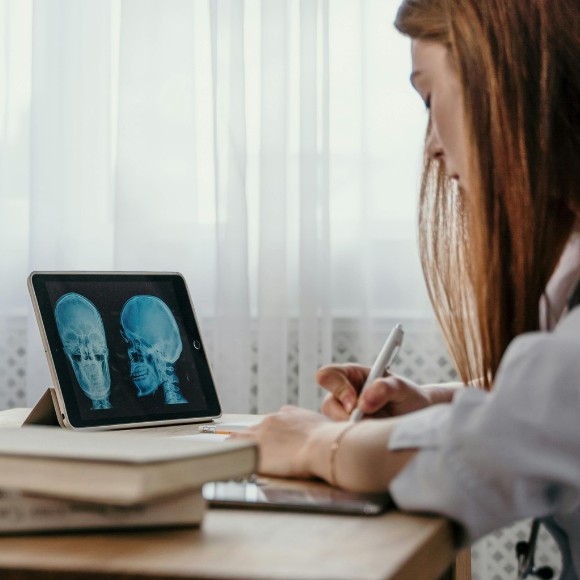 Patient reviewing brain scan images on a tablet while taking notes at home.