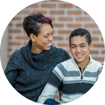 Two people sitting together outdoors, smiling and sharing a supportive moment.