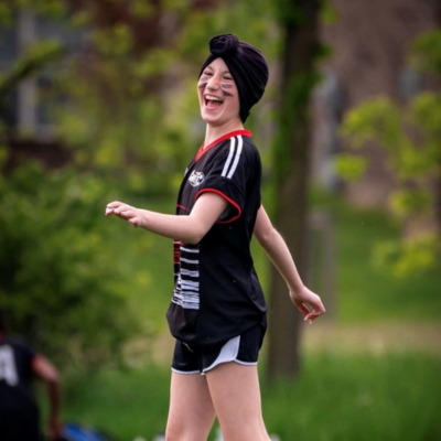 Young person laughing while walking outdoors during a group activity.