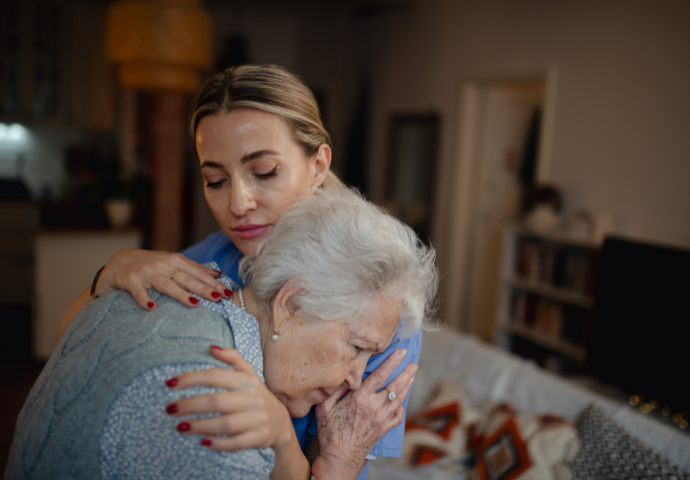 A young woman offers comfort to an elderly woman in a comfortable home setting. Evokes care and support during a difficult time.