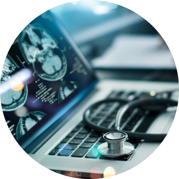 A laptop displays brain imaging scans on its screen, with a stethoscope resting on the keyboard, symbolizing medical review and diagnostic decision-making.
