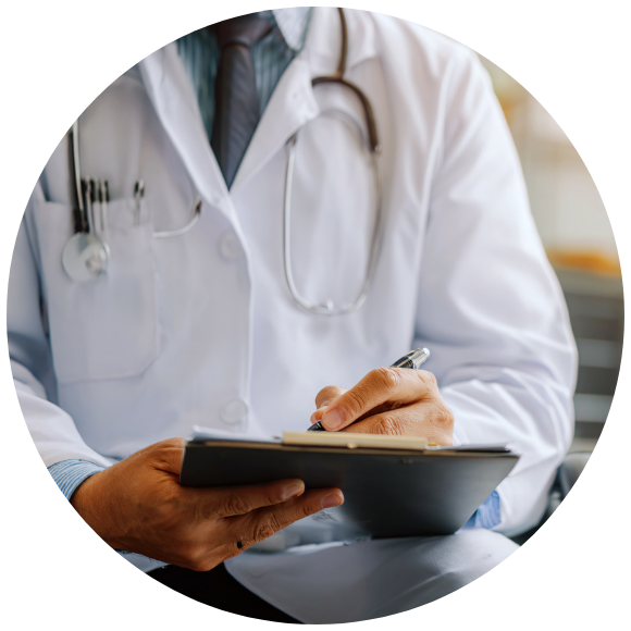 A male physician sitting in a chair taking notes during a consultation